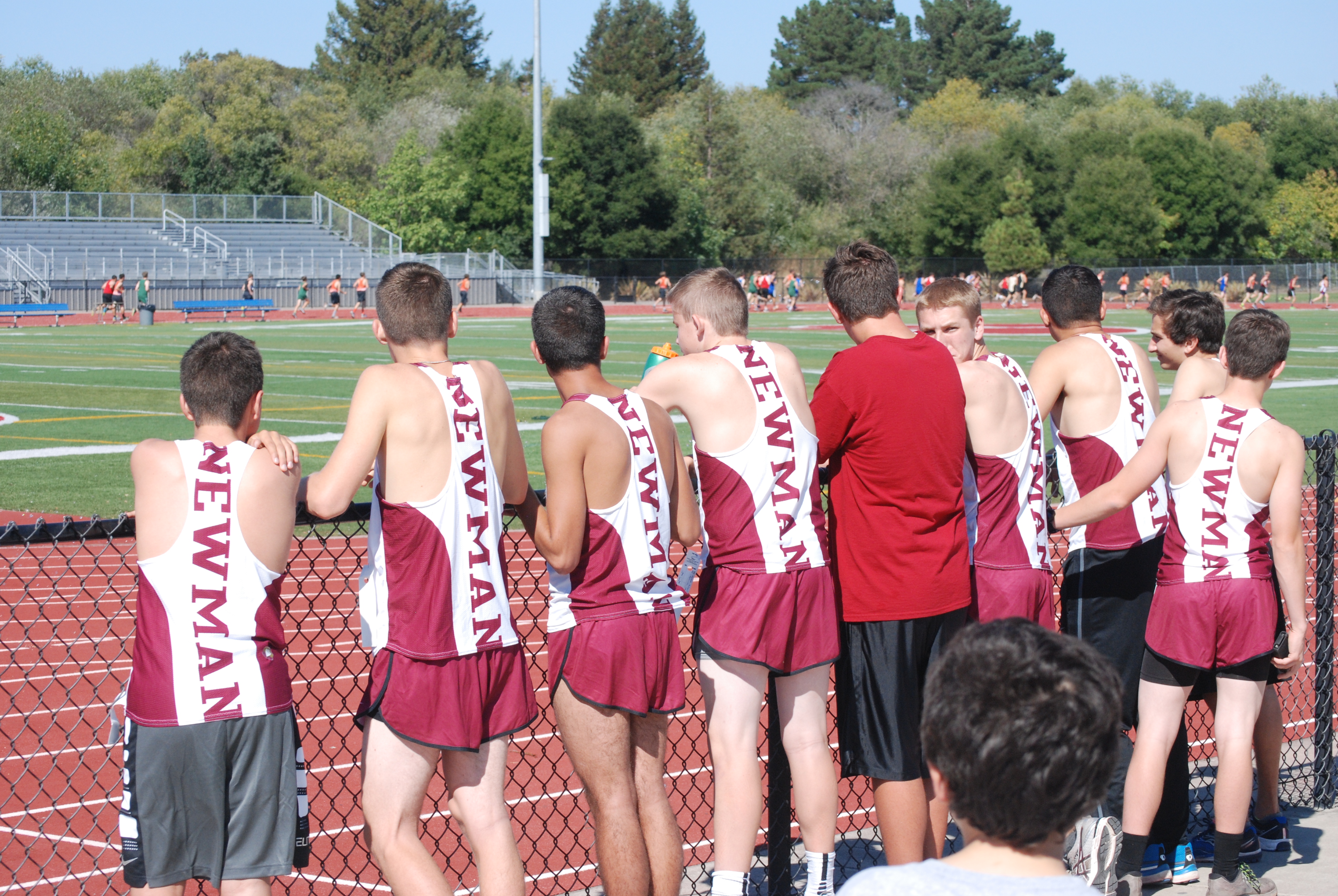 Athlete prepares for pole vault on a track with others watching.