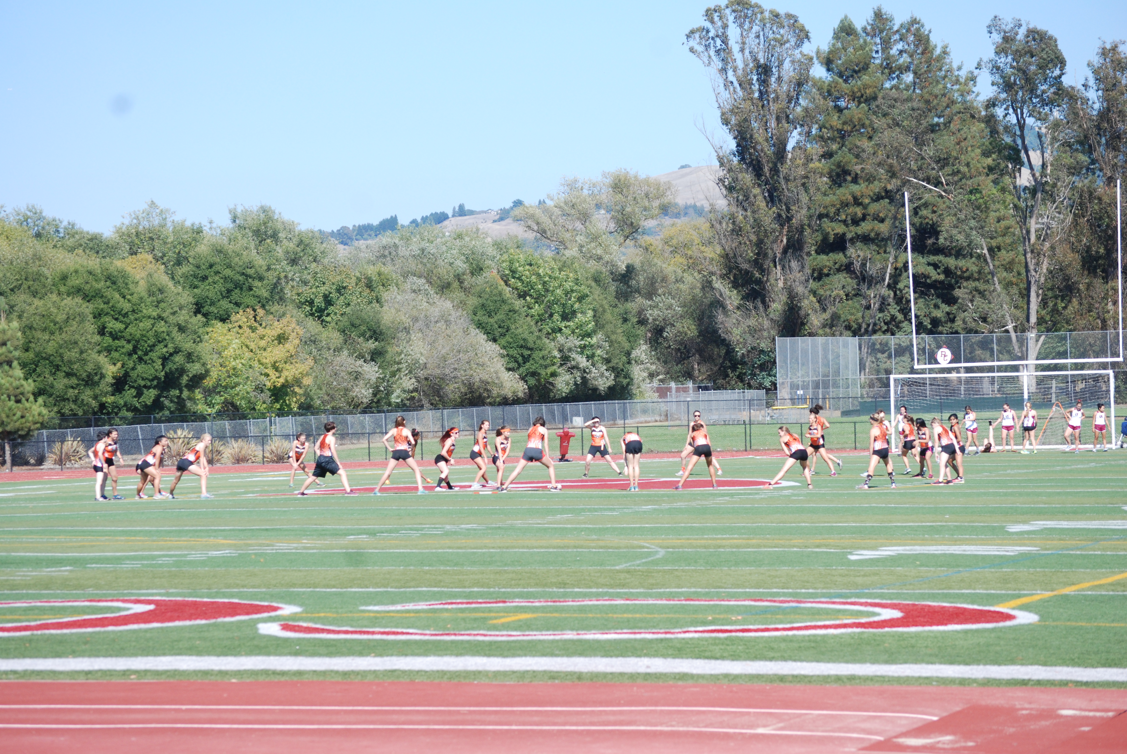 Athlete prepares for pole vault on a track with others watching.
