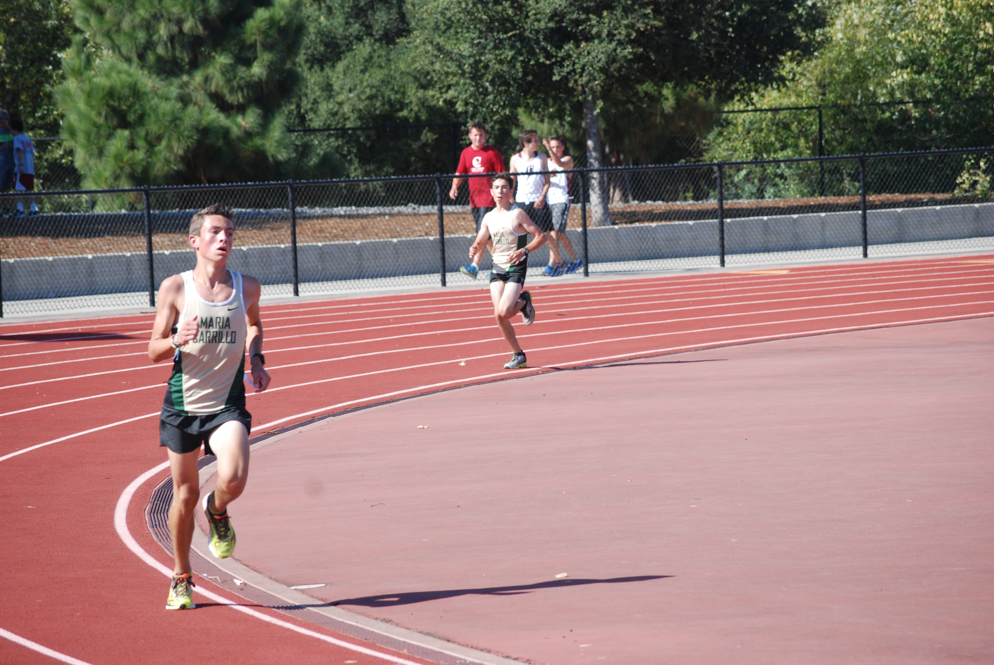 Athlete prepares for pole vault on a track with others watching.