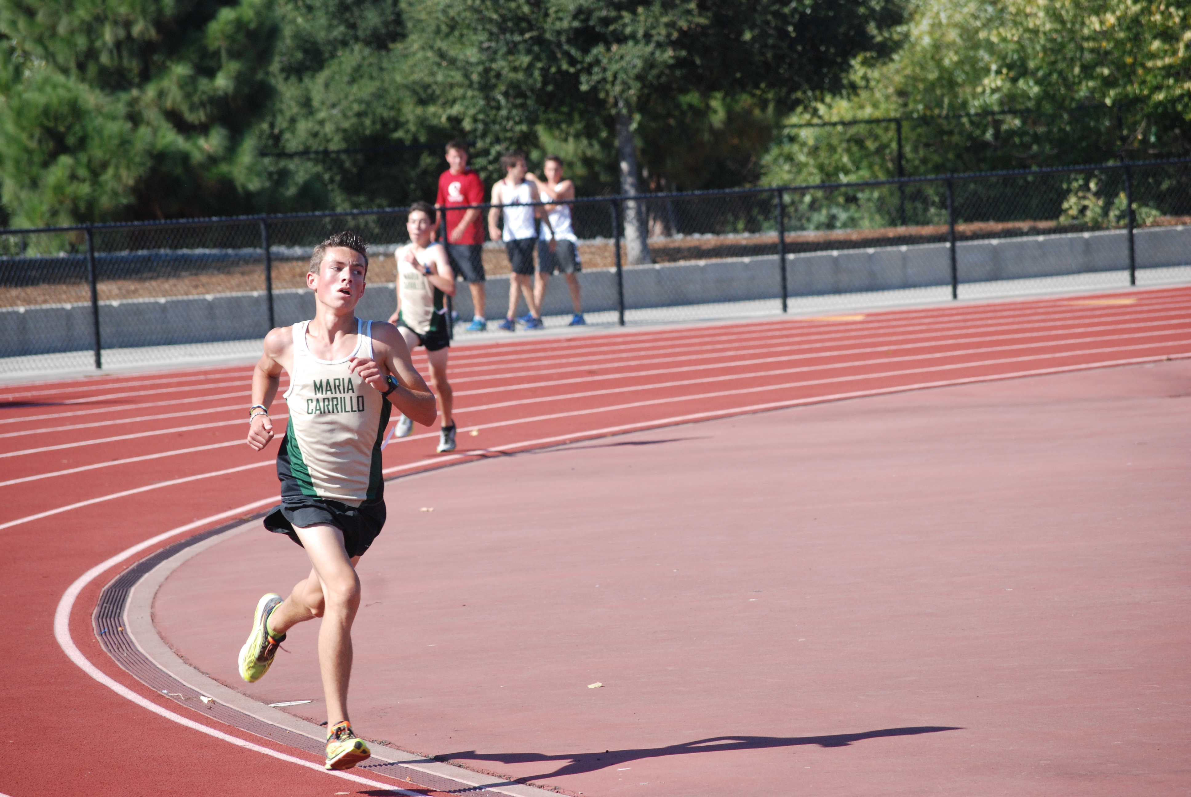 Athlete prepares for pole vault on a track with others watching.