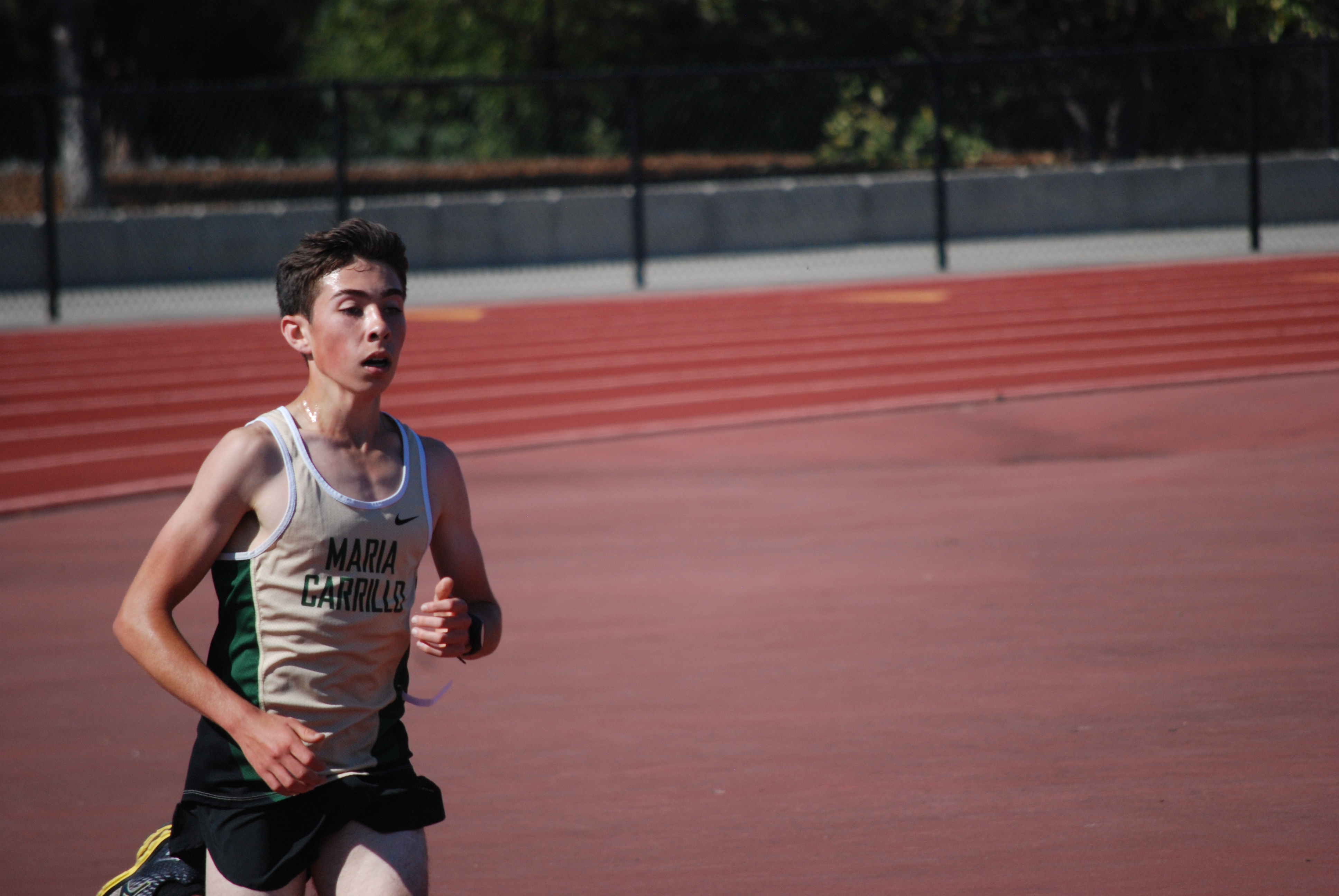 Athlete prepares for pole vault on a track with others watching.