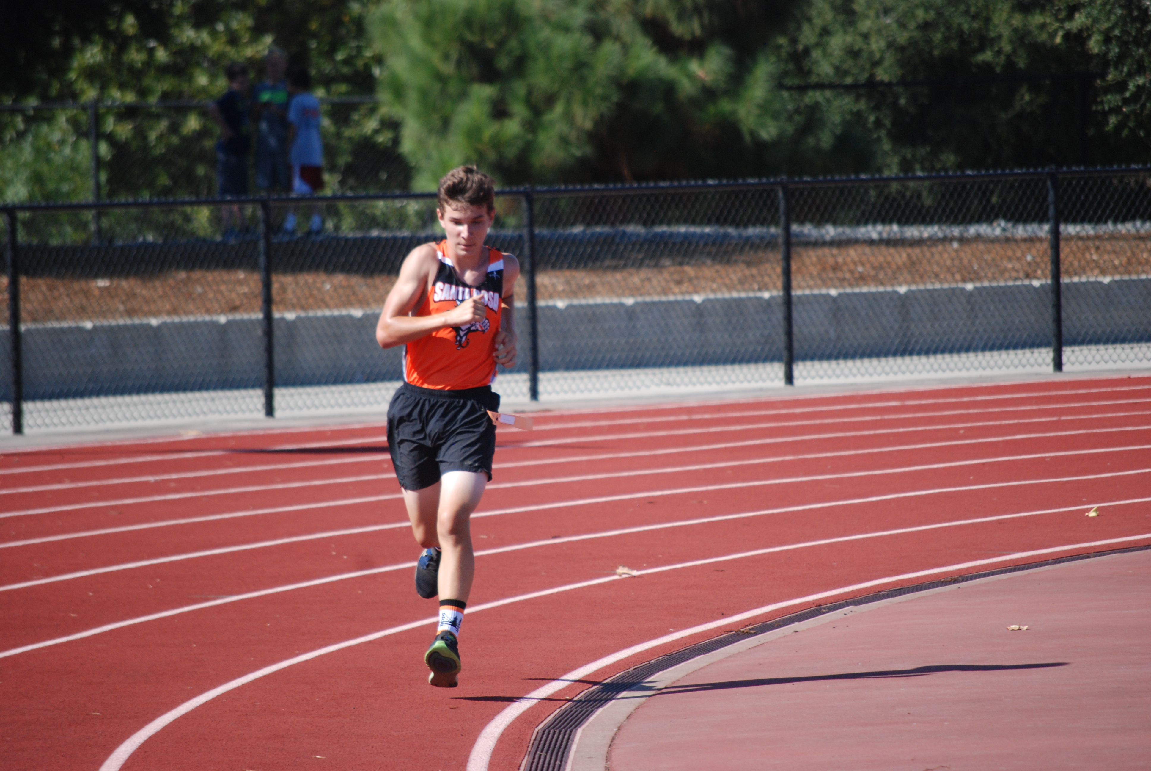 Athlete prepares for pole vault on a track with others watching.