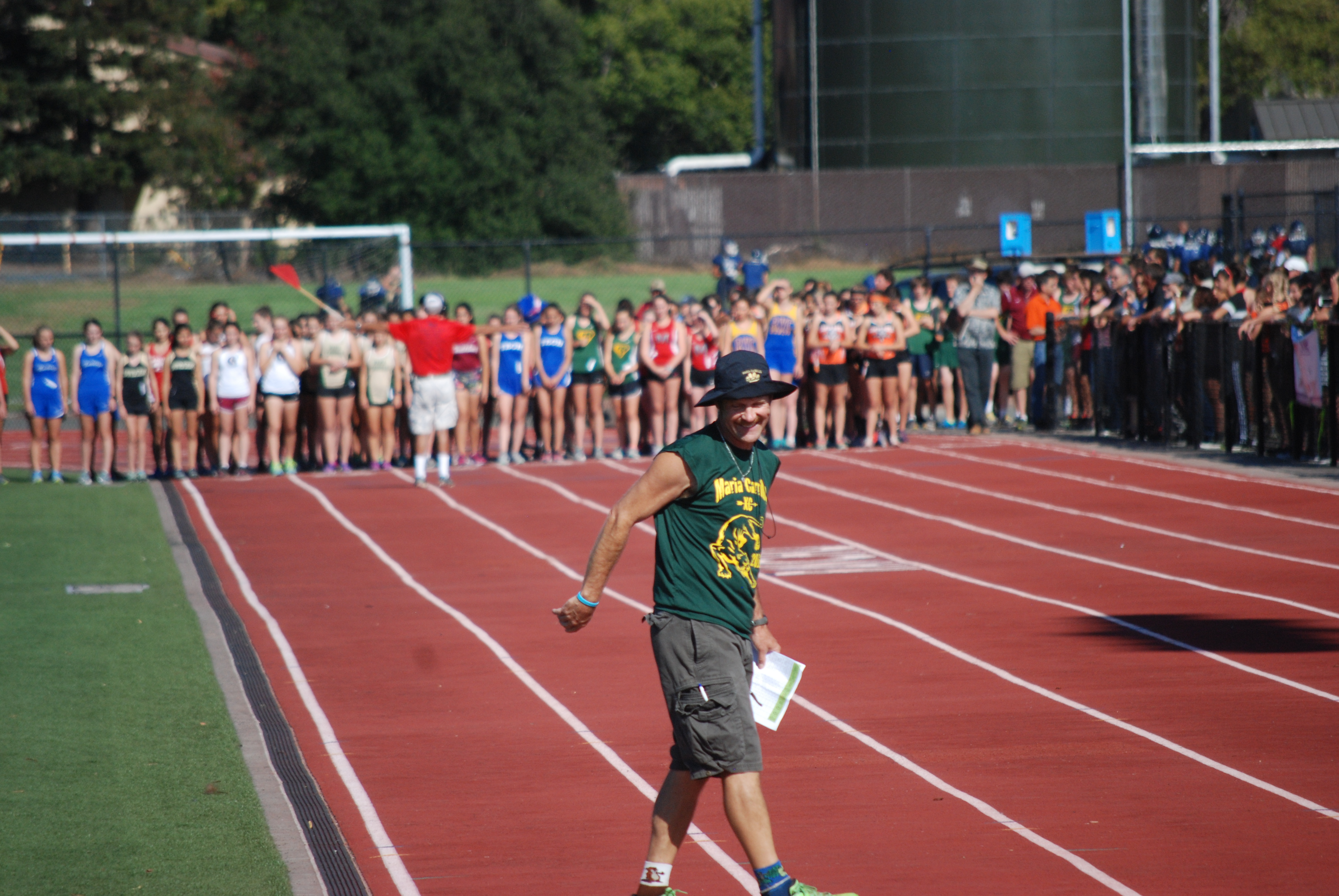 Athlete prepares for pole vault on a track with others watching.