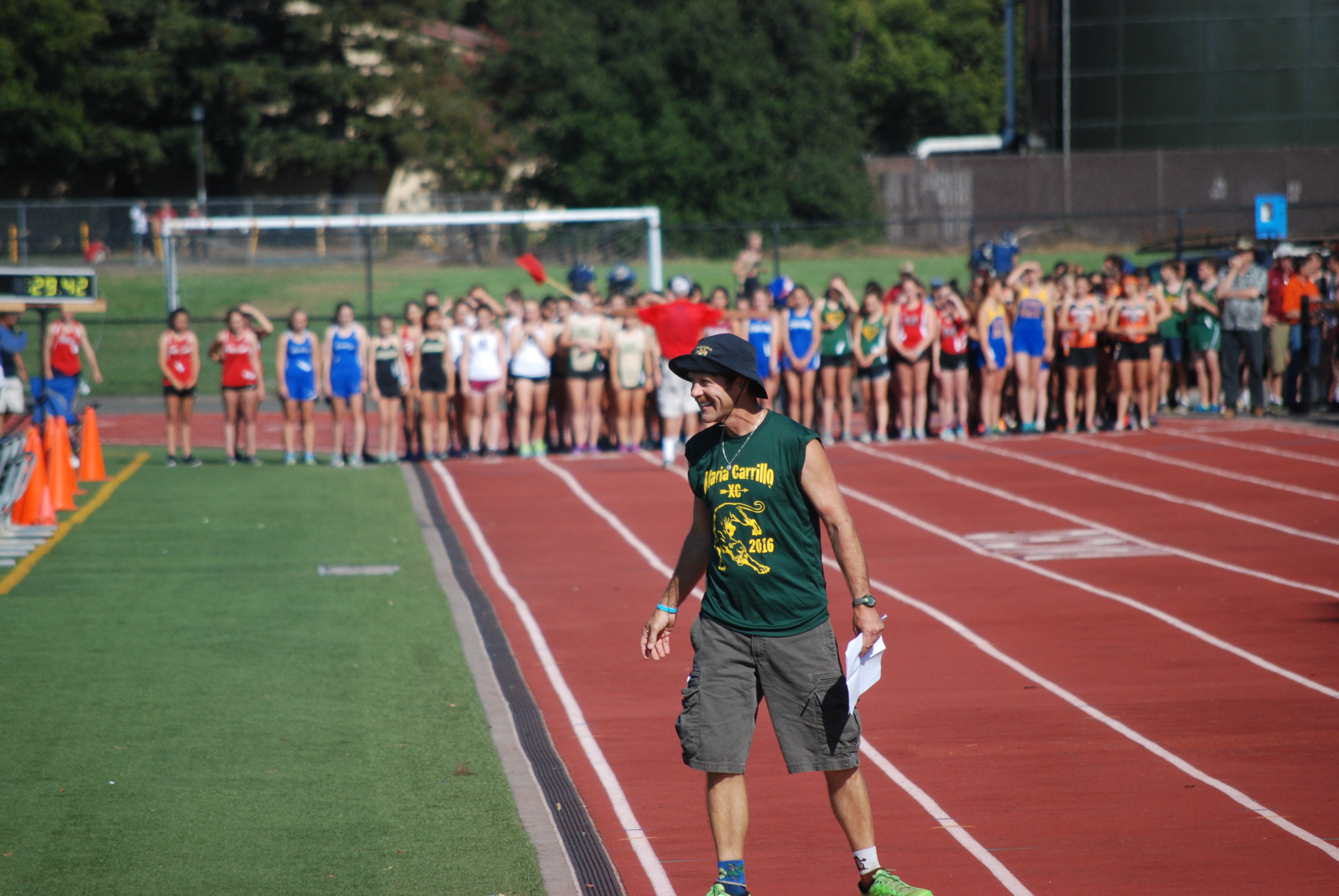 Athlete prepares for pole vault on a track with others watching.