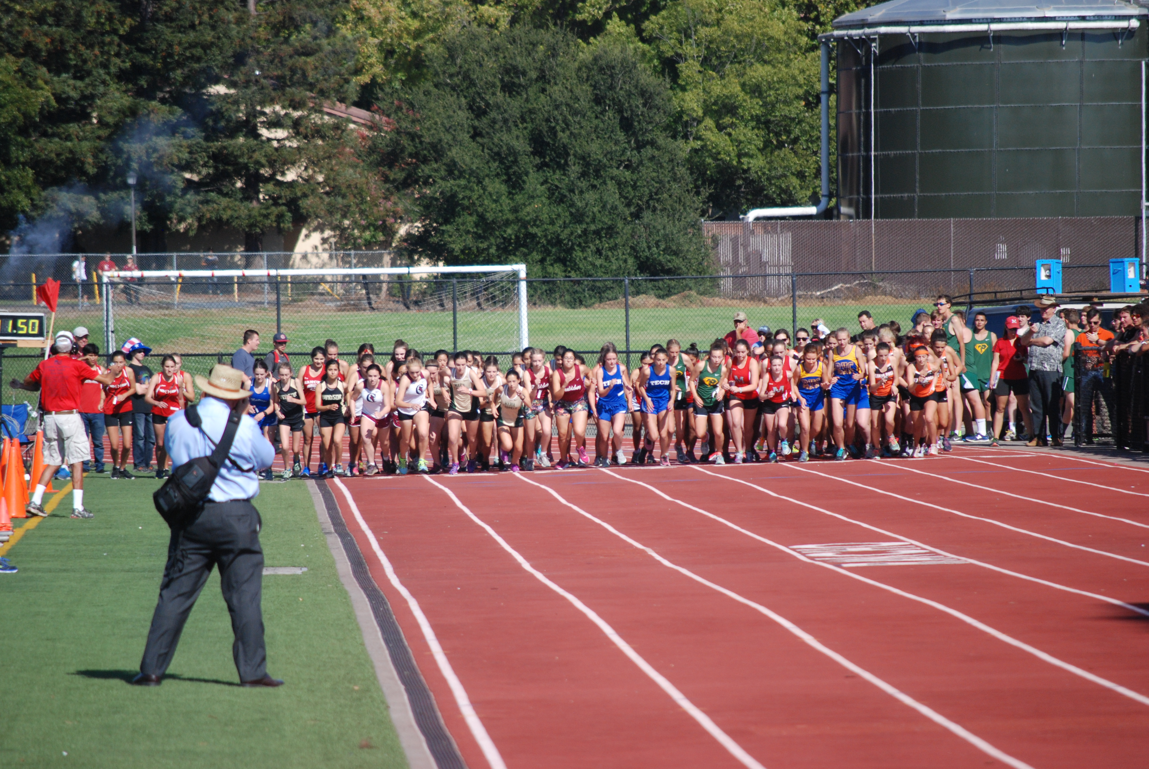 Athlete prepares for pole vault on a track with others watching.