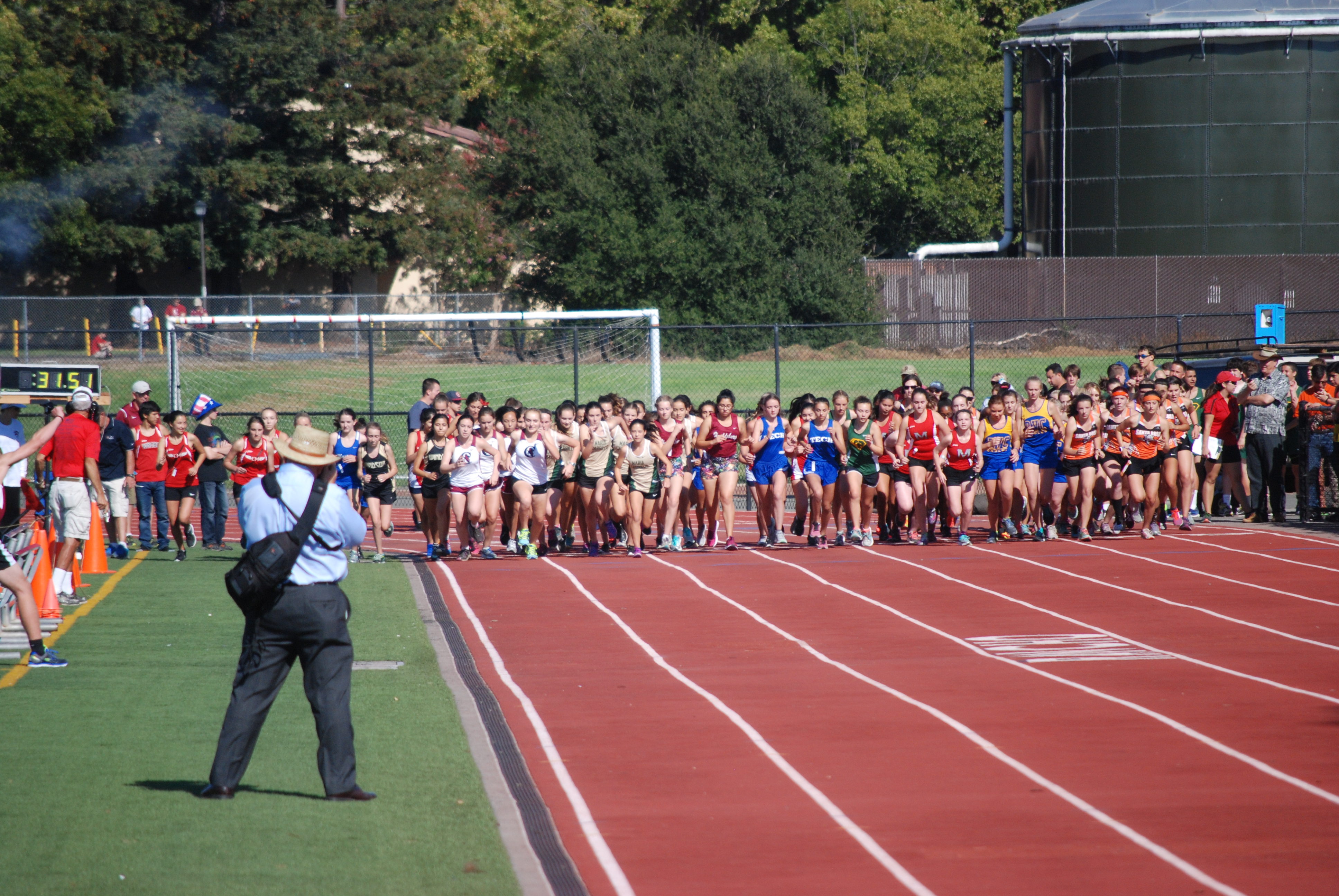 Athlete prepares for pole vault on a track with others watching.