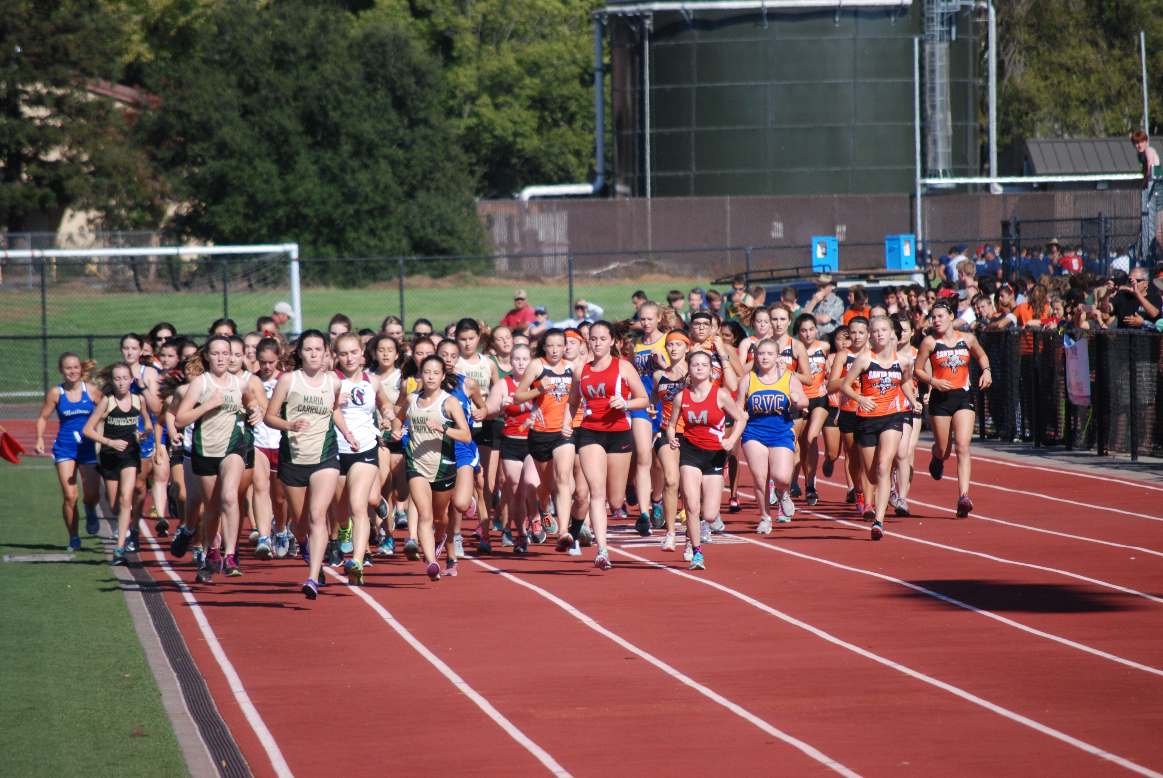 Athlete prepares for pole vault on a track with others watching.