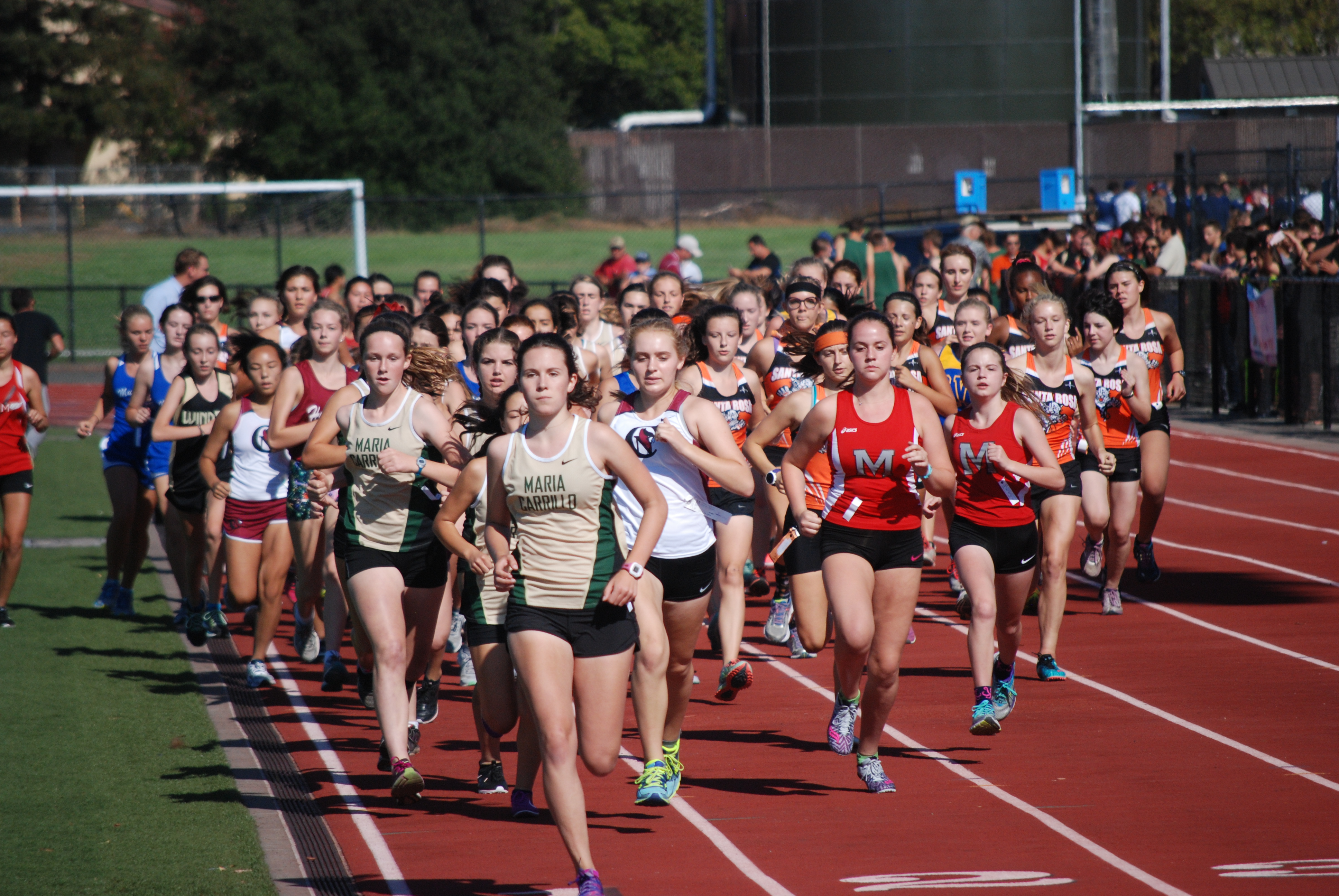 Athlete prepares for pole vault on a track with others watching.