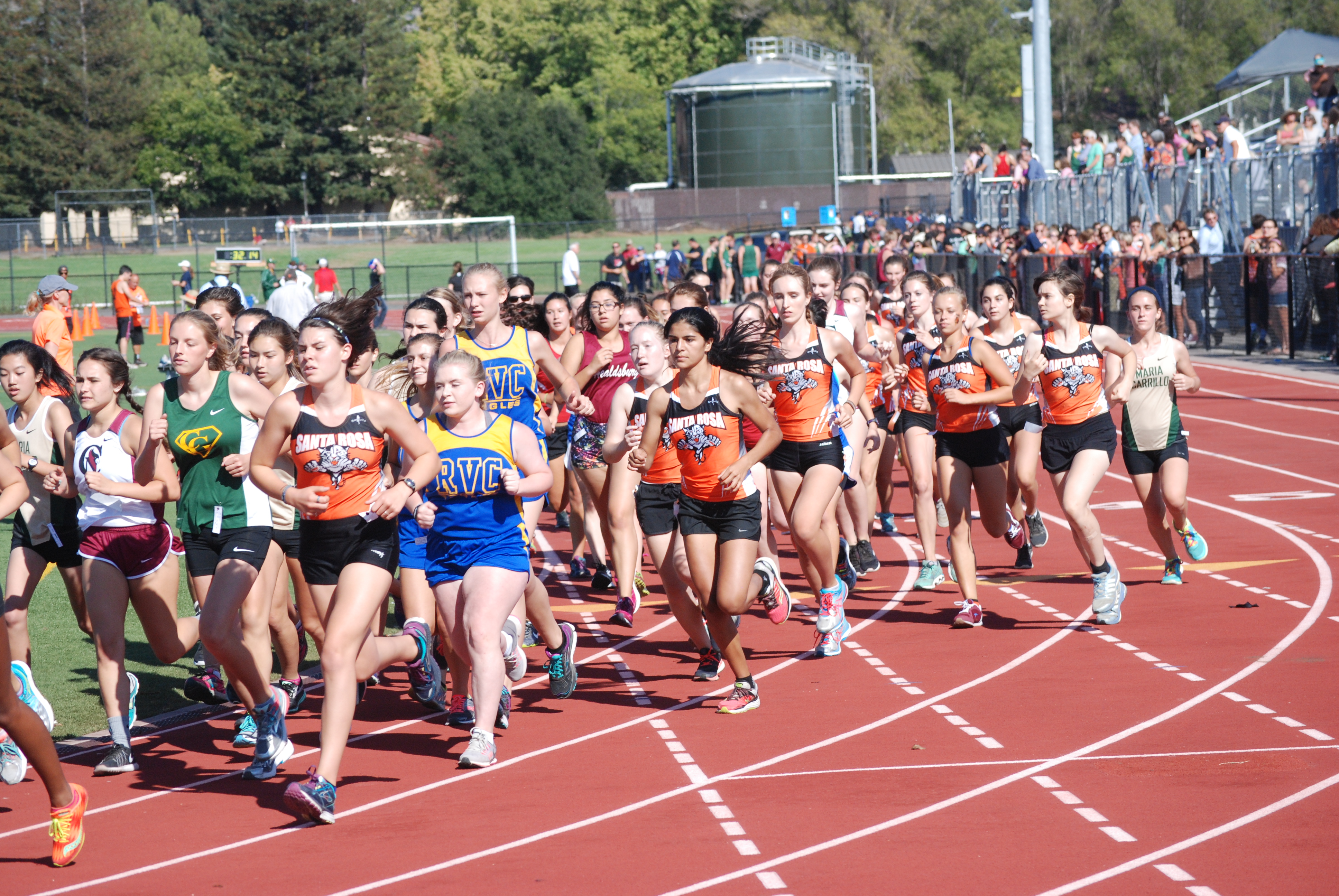 Athlete prepares for pole vault on a track with others watching.