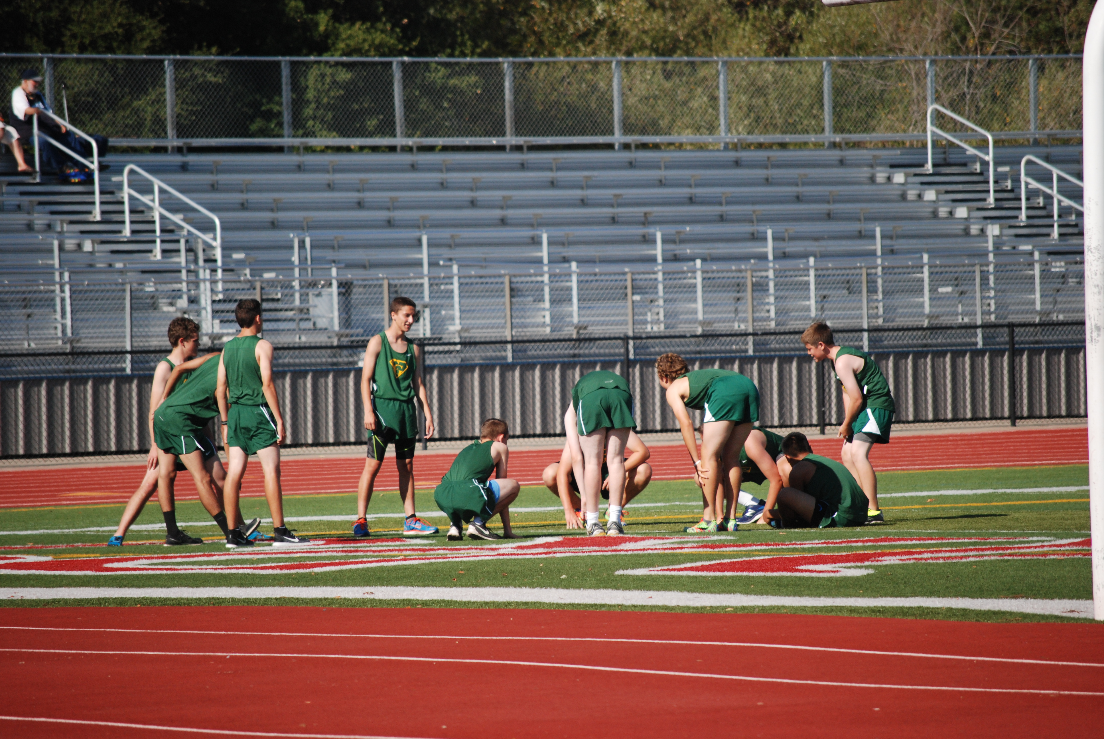 Athlete prepares for pole vault on a track with others watching.