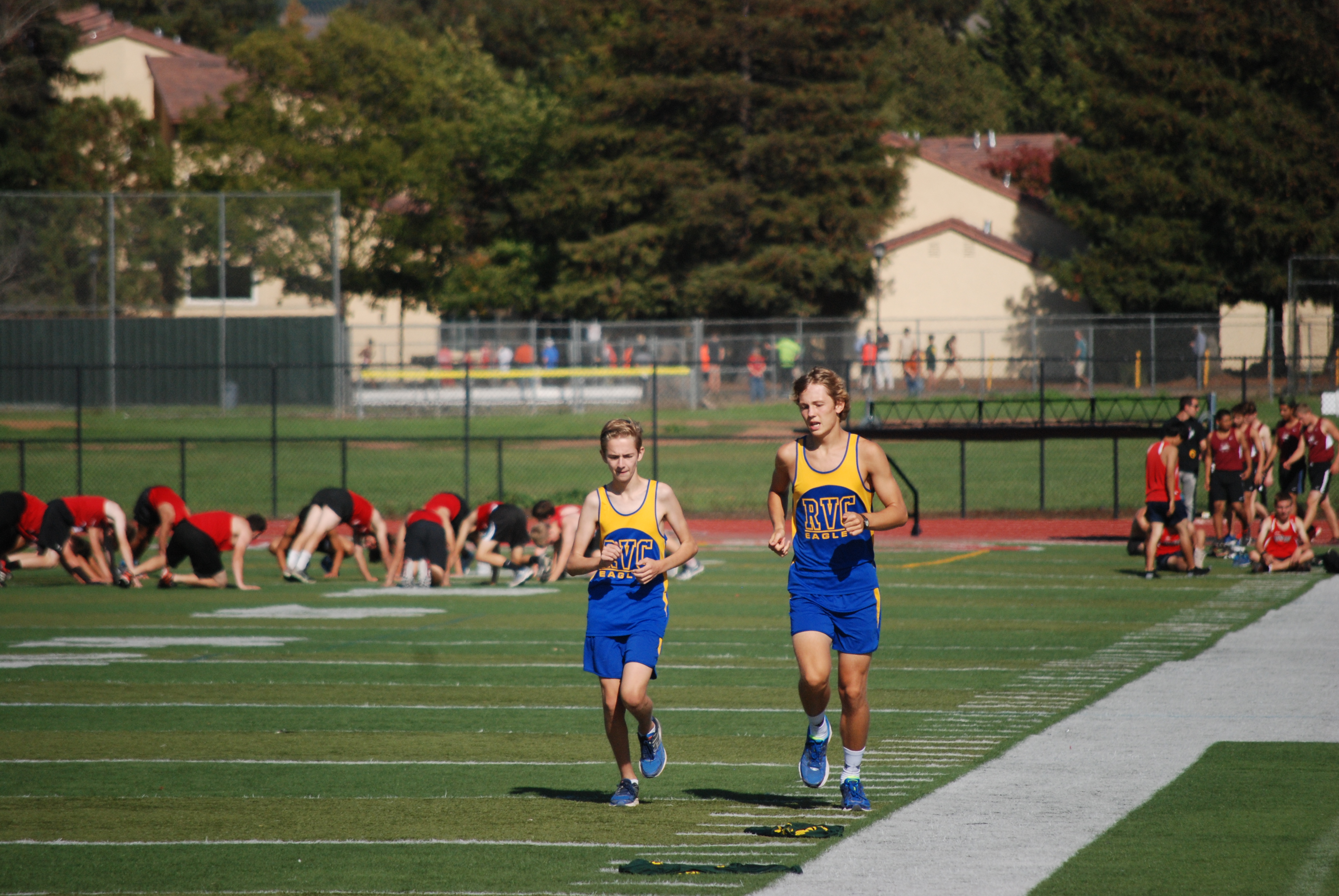 Athlete prepares for pole vault on a track with others watching.