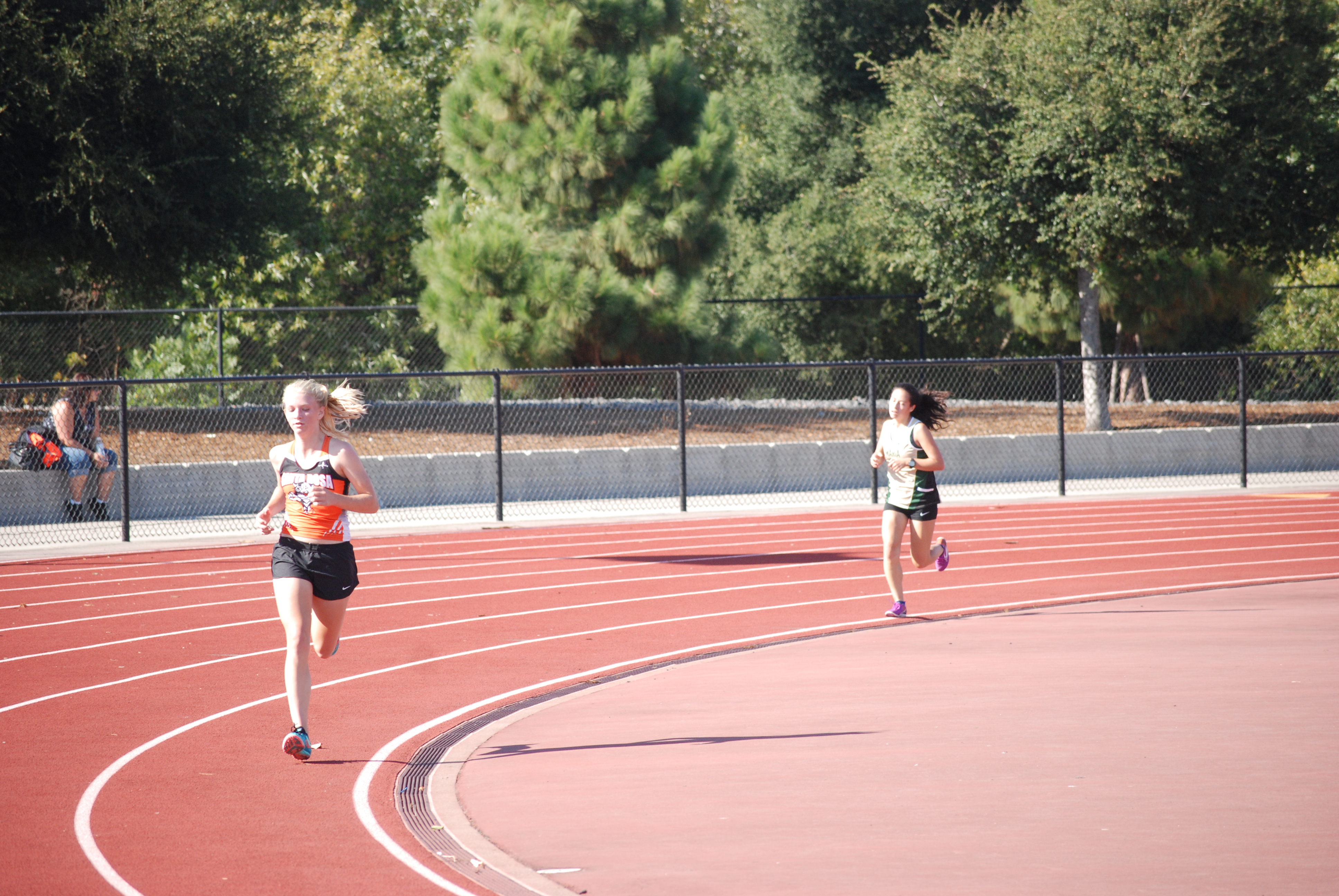 Athlete prepares for pole vault on a track with others watching.