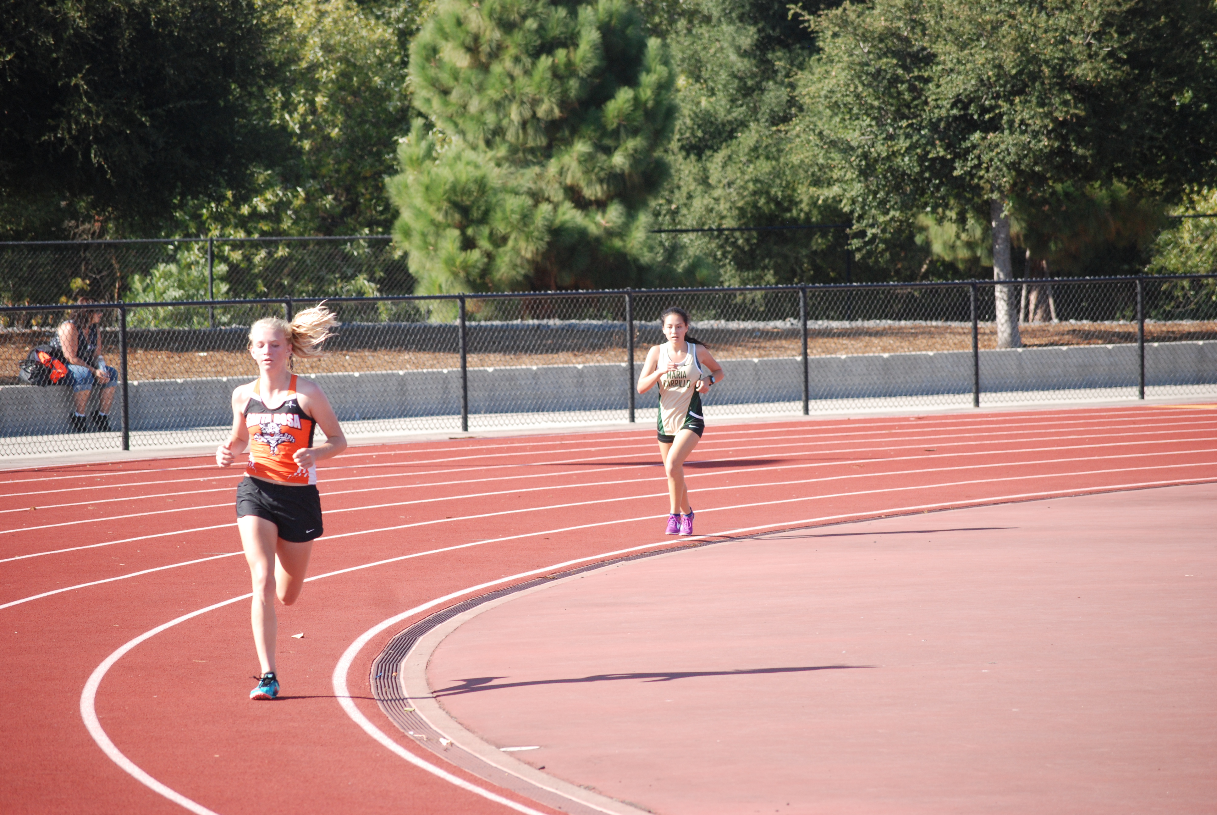 Athlete prepares for pole vault on a track with others watching.