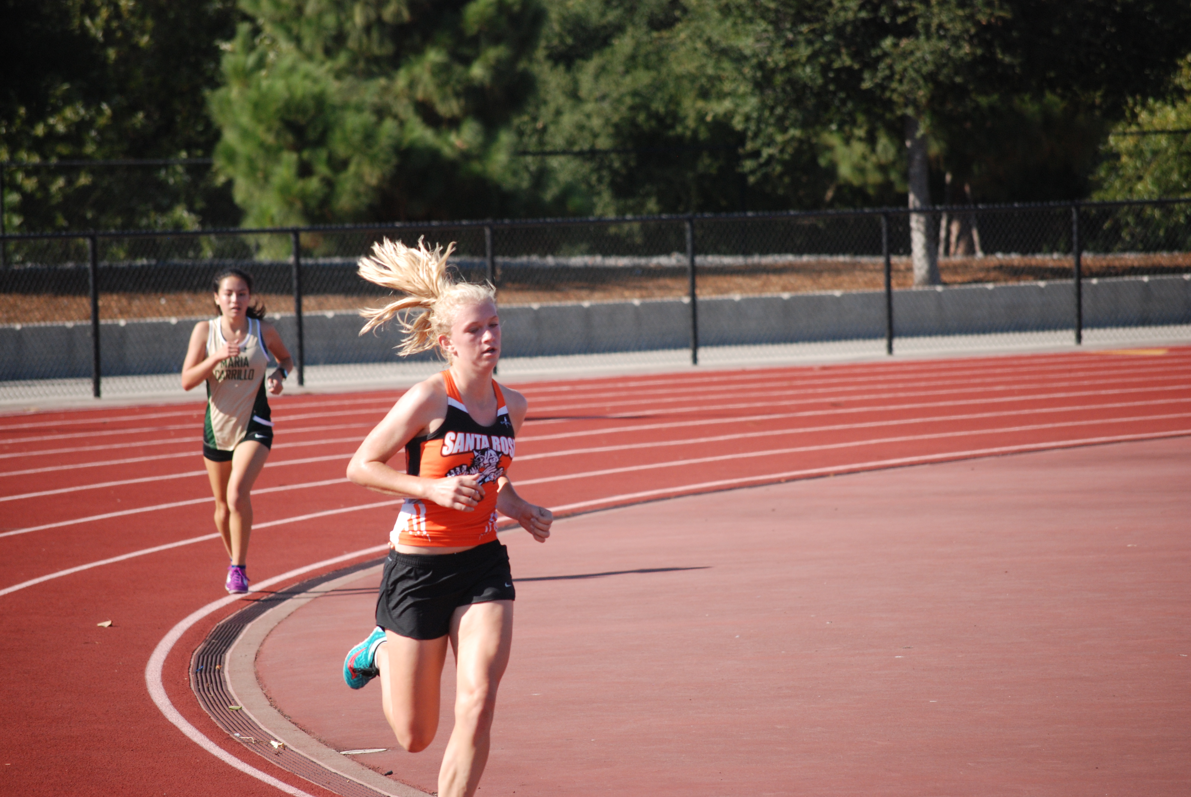 Athlete prepares for pole vault on a track with others watching.