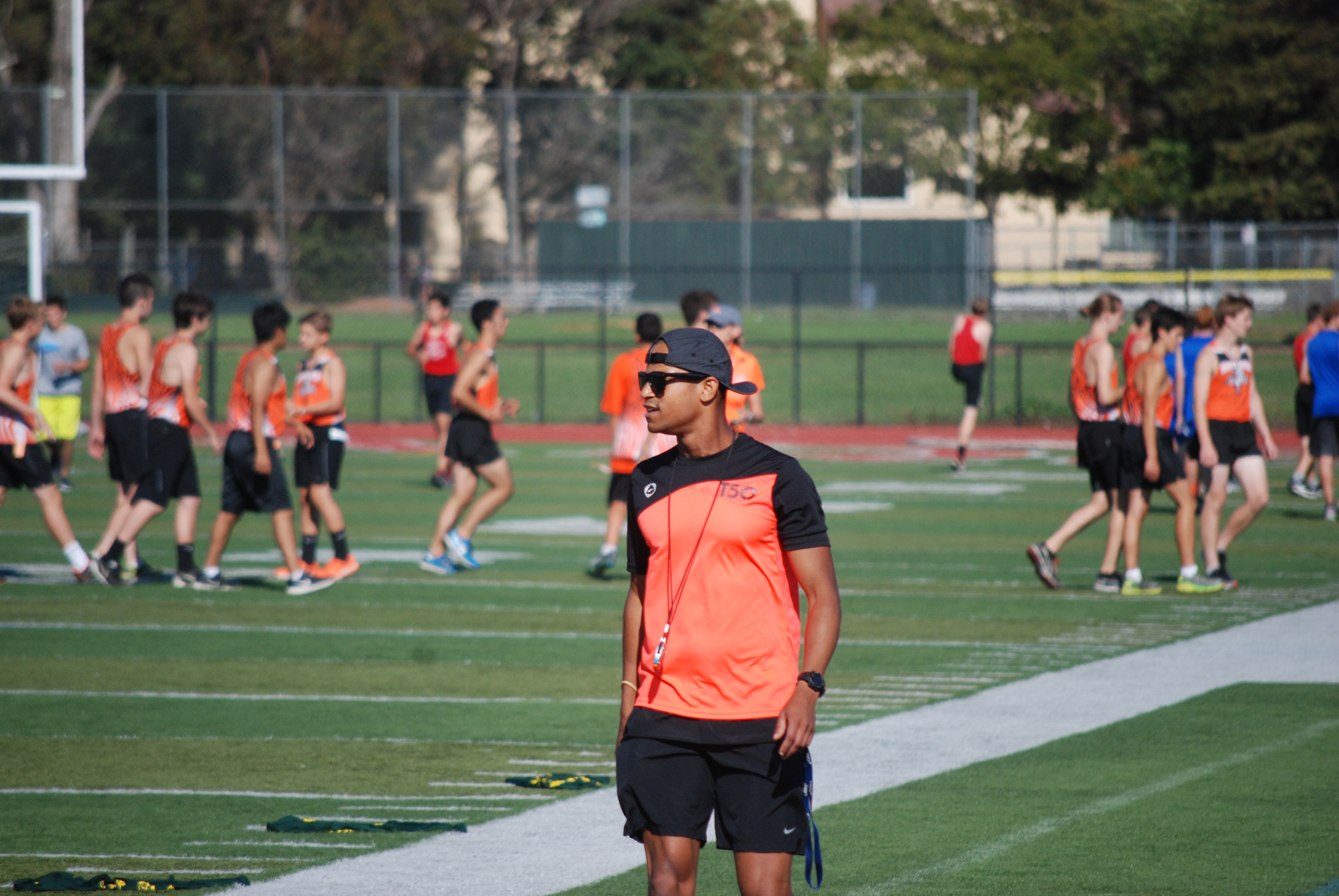 Athlete prepares for pole vault on a track with others watching.