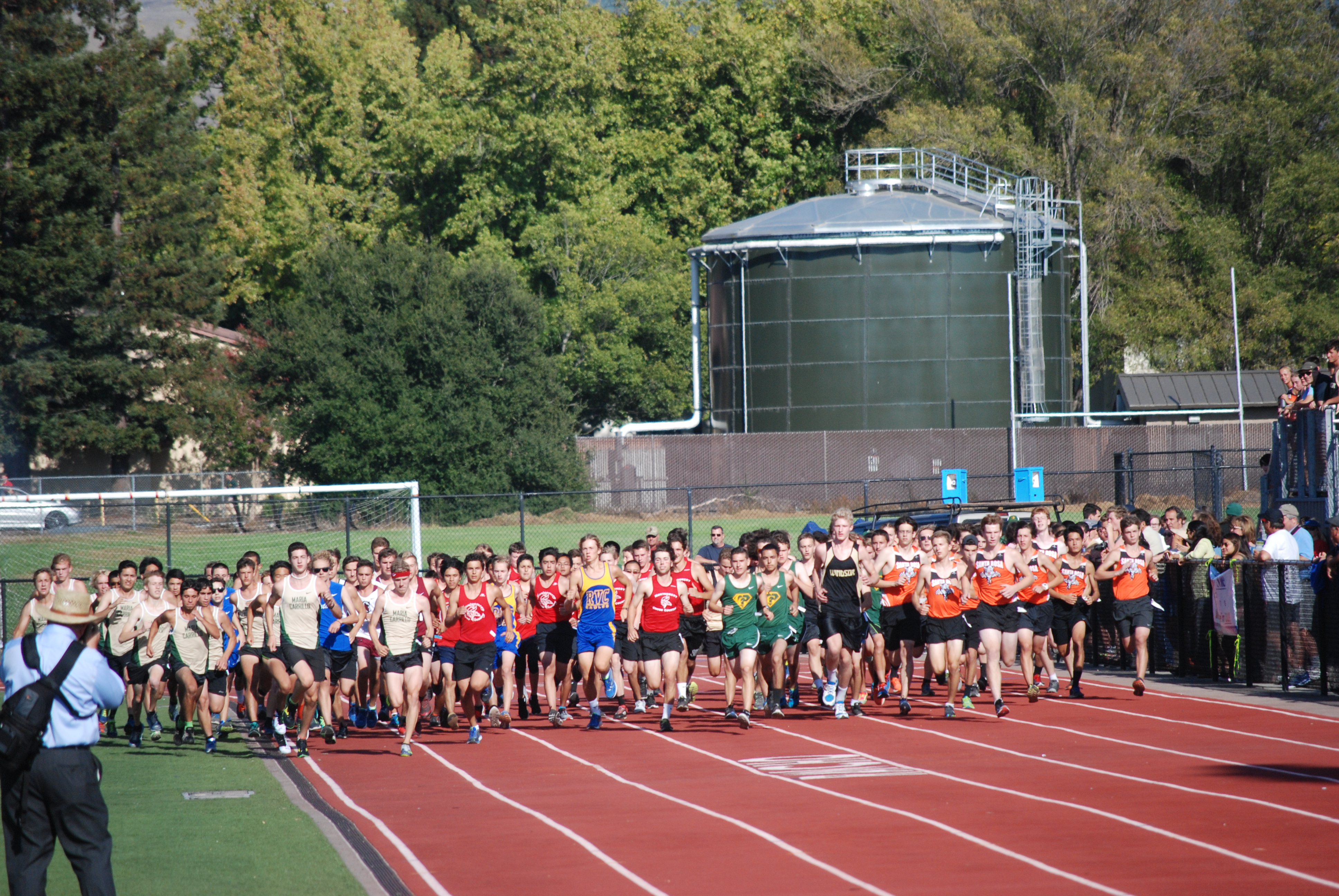Athlete prepares for pole vault on a track with others watching.