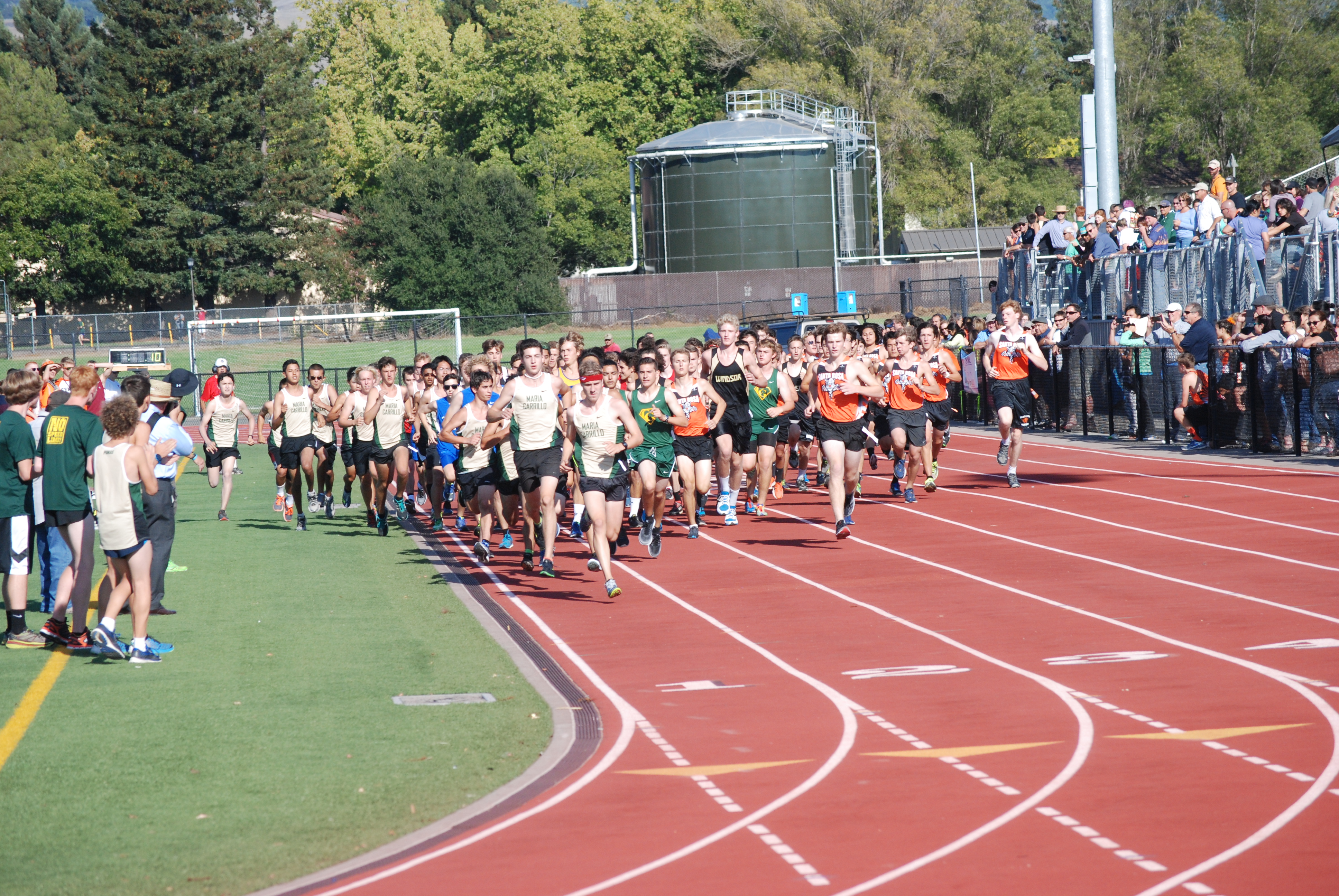 Athlete prepares for pole vault on a track with others watching.