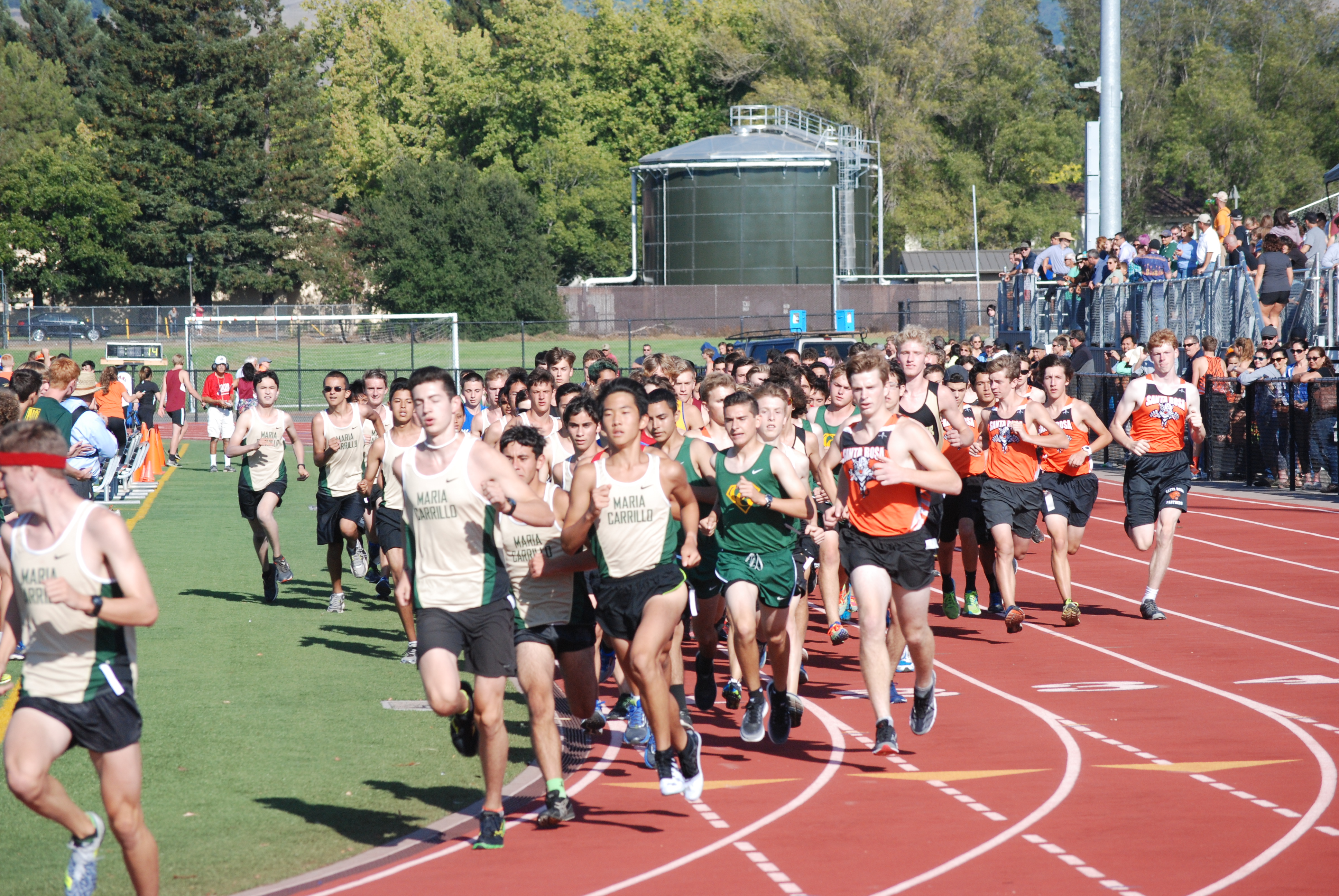 Athlete prepares for pole vault on a track with others watching.