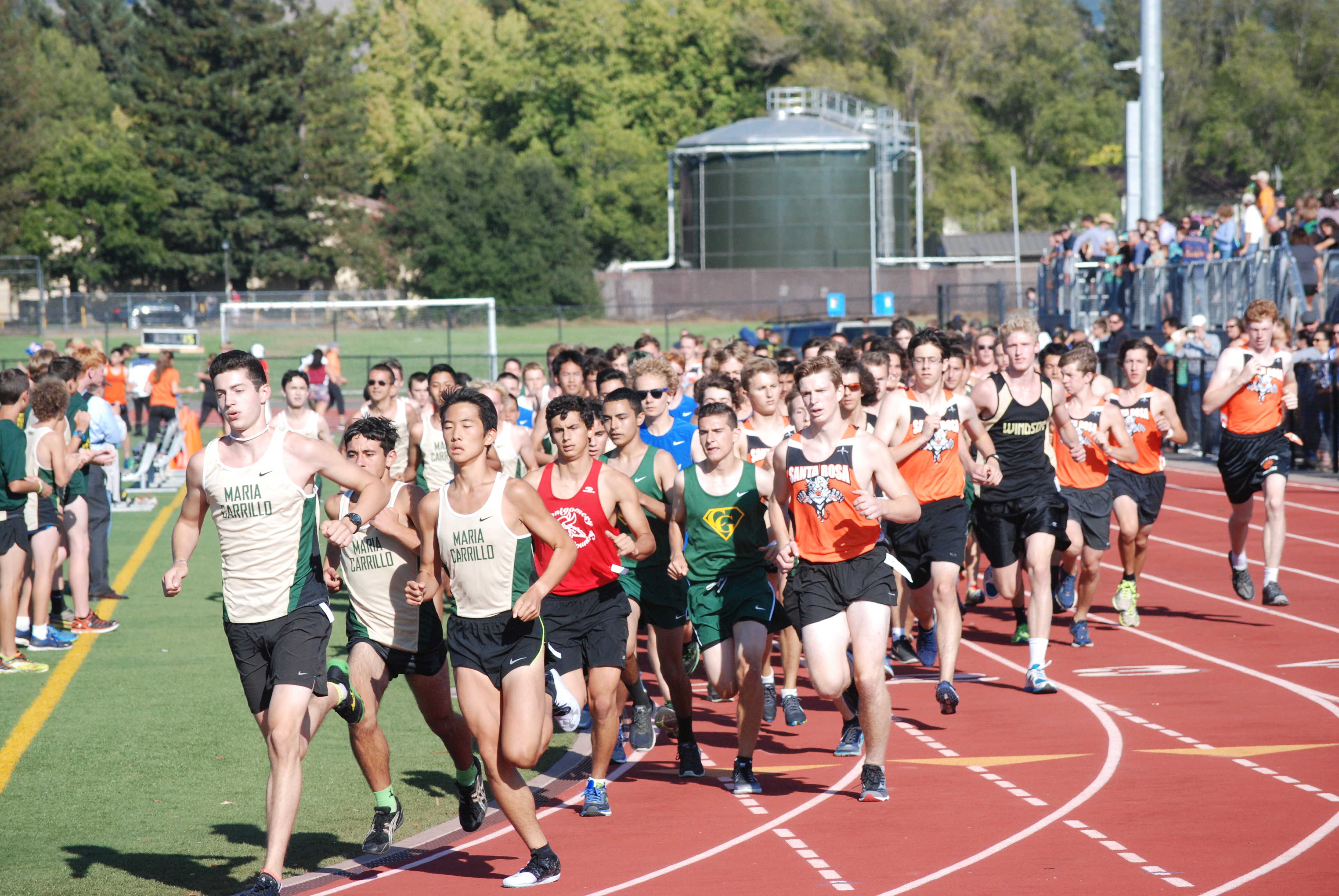 Athlete prepares for pole vault on a track with others watching.