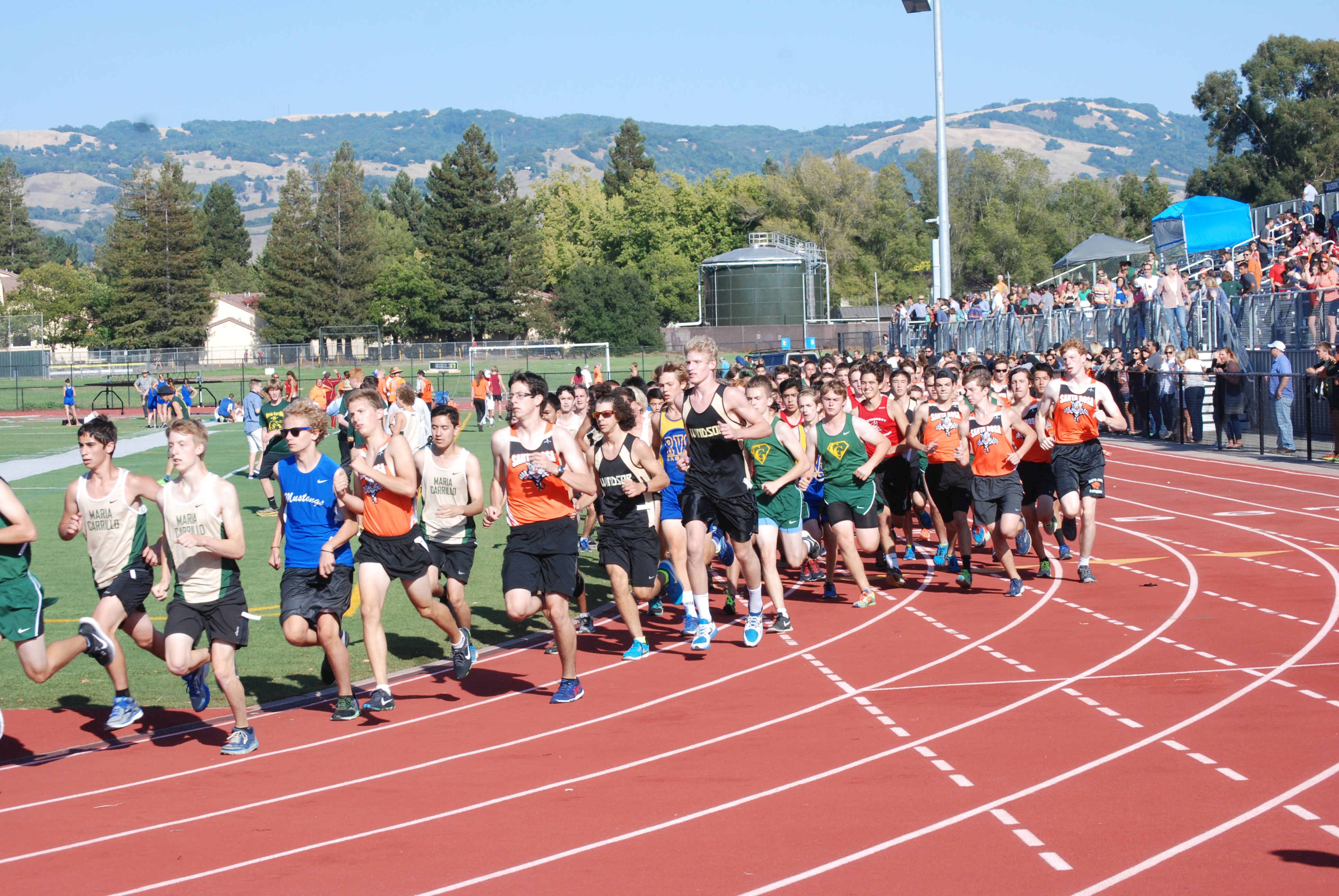 Athlete prepares for pole vault on a track with others watching.