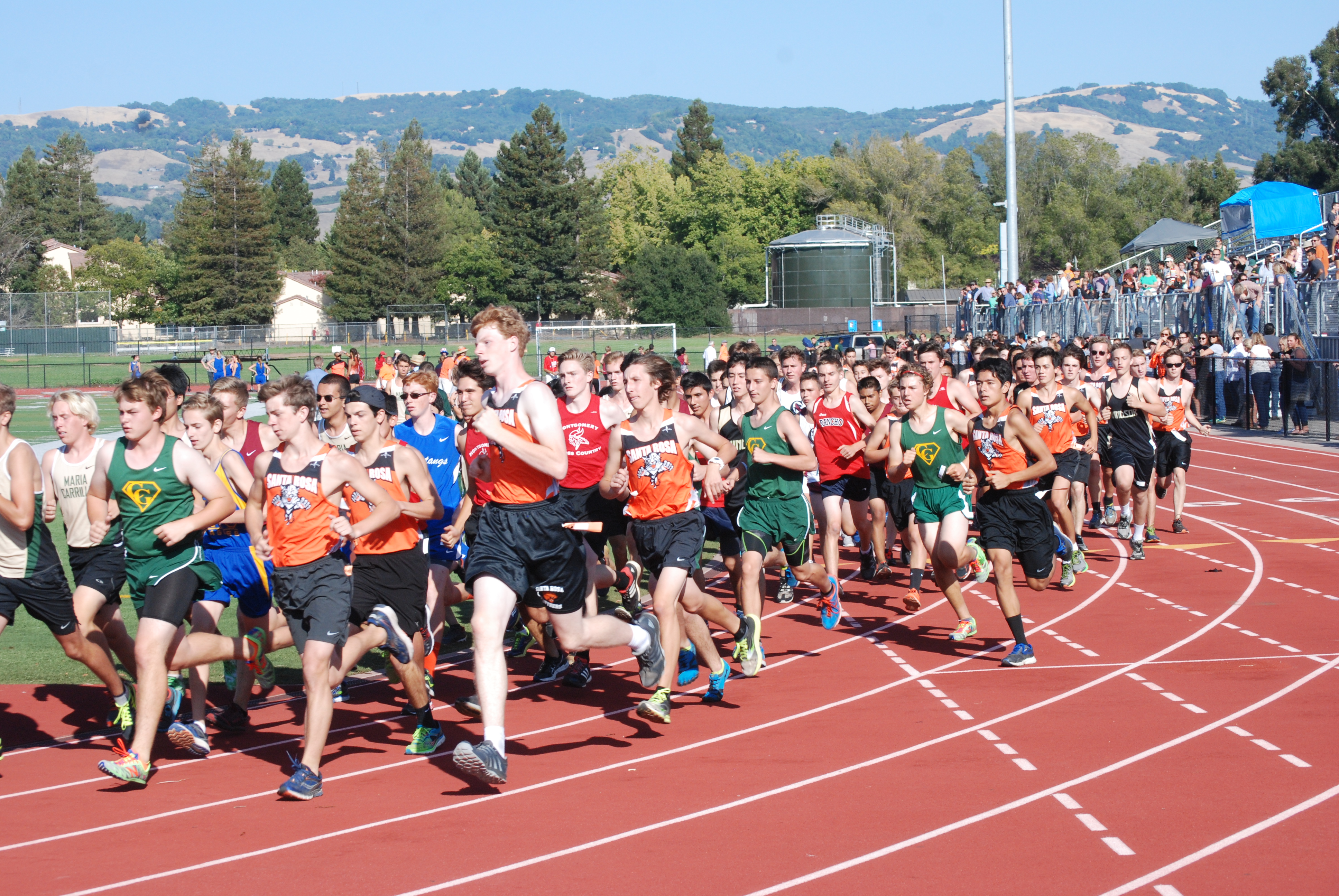 Athlete prepares for pole vault on a track with others watching.