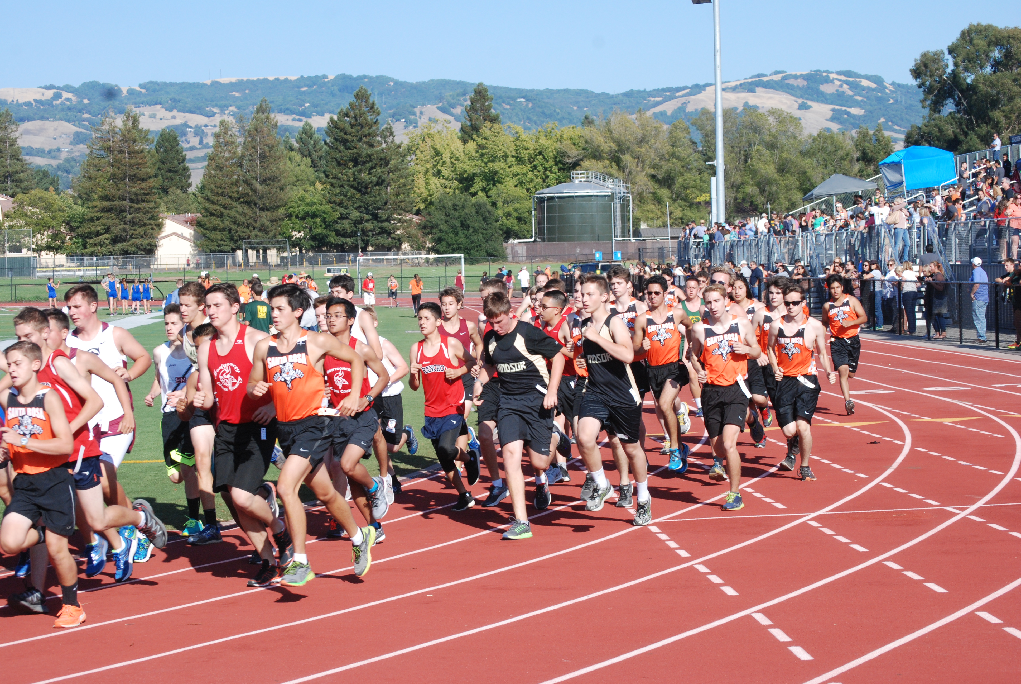 Athlete prepares for pole vault on a track with others watching.