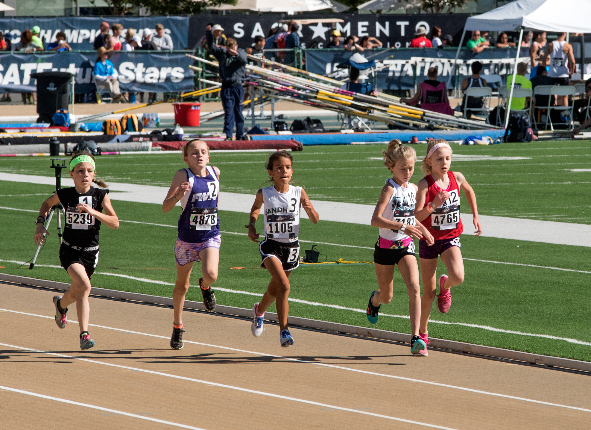 Athlete prepares for pole vault on a track with others watching.