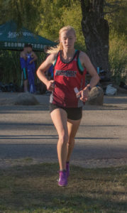 Athlete prepares for pole vault on a track with others watching.