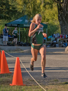 Athlete prepares for pole vault on a track with others watching.