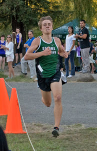 Athlete prepares for pole vault on a track with others watching.