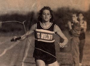 Athlete prepares for pole vault on a track with others watching.