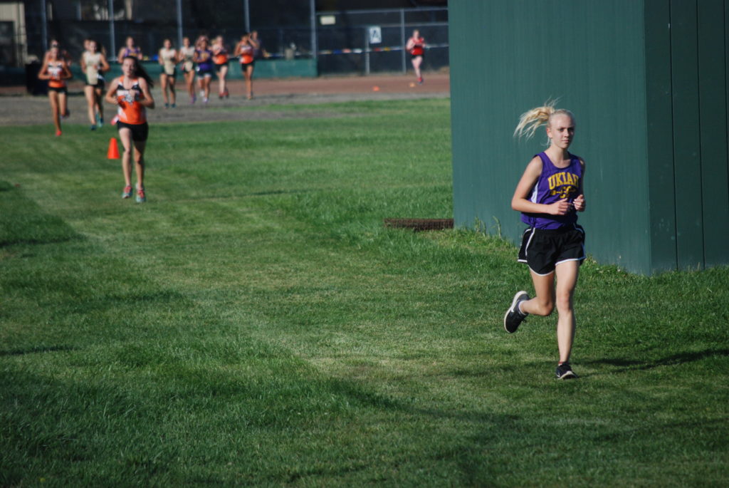 Athlete prepares for pole vault on a track with others watching.