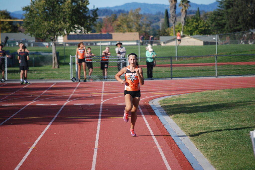 Athlete prepares for pole vault on a track with others watching.