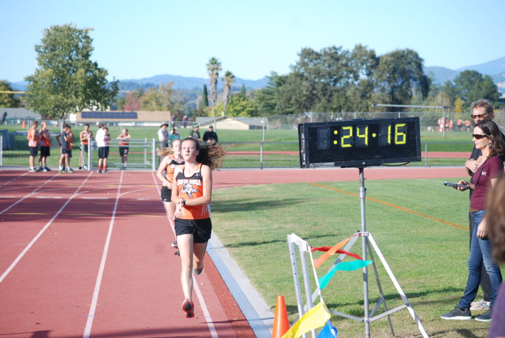 Athlete prepares for pole vault on a track with others watching.
