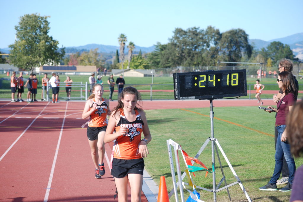 Athlete prepares for pole vault on a track with others watching.