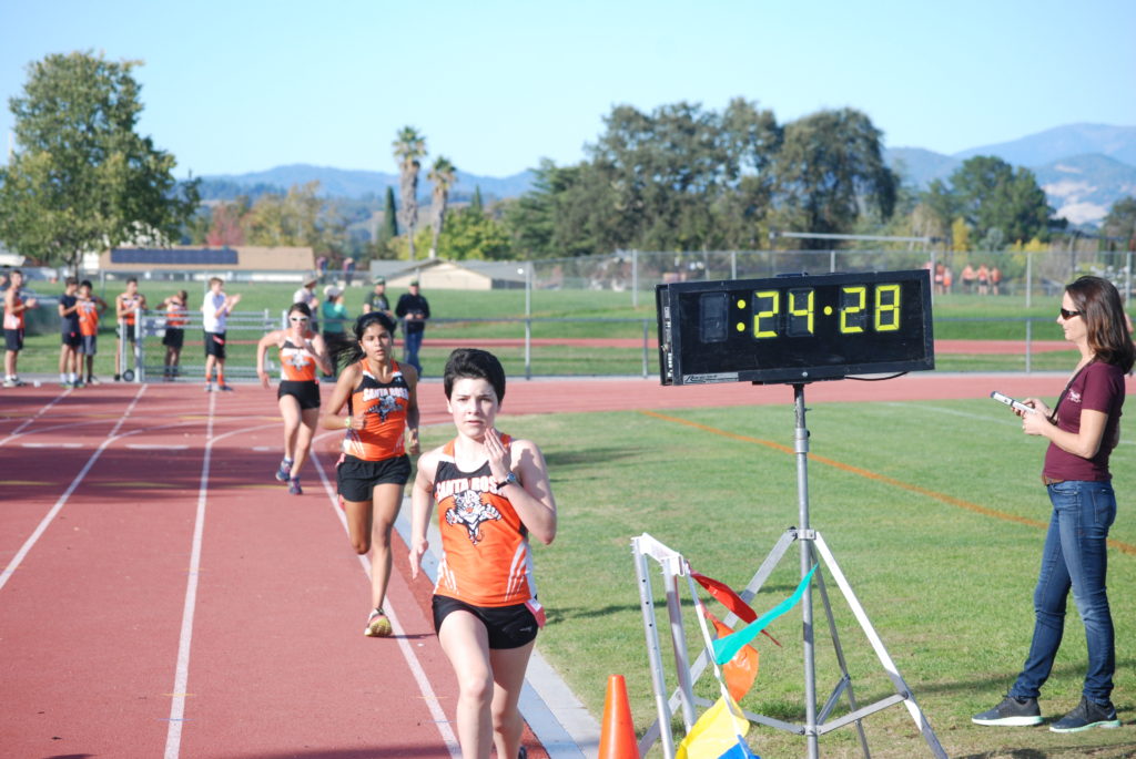 Athlete prepares for pole vault on a track with others watching.