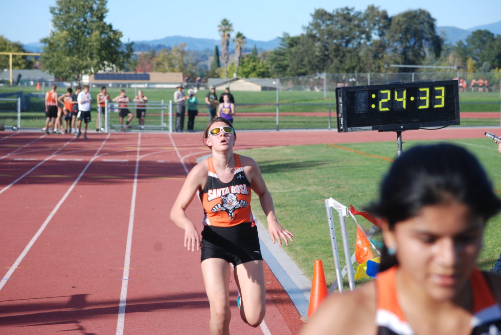 Athlete prepares for pole vault on a track with others watching.
