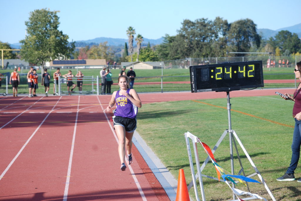 Athlete prepares for pole vault on a track with others watching.
