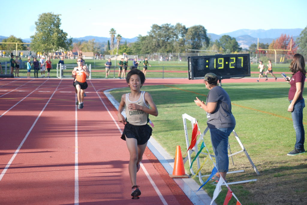 Athlete prepares for pole vault on a track with others watching.