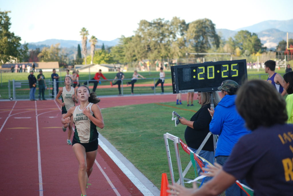 Athlete prepares for pole vault on a track with others watching.