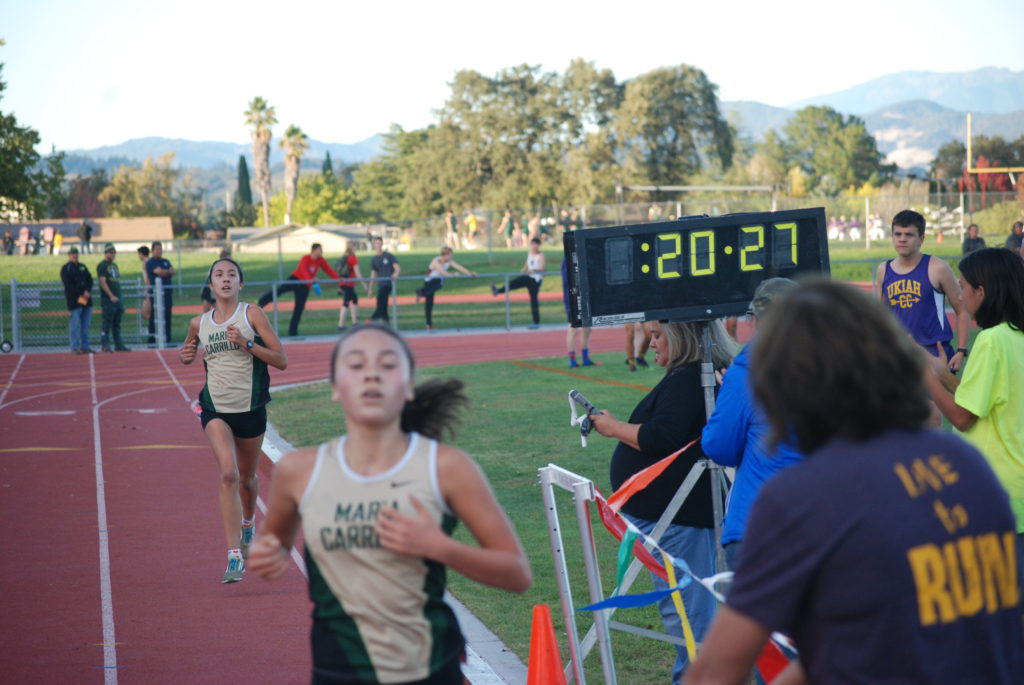 Athlete prepares for pole vault on a track with others watching.