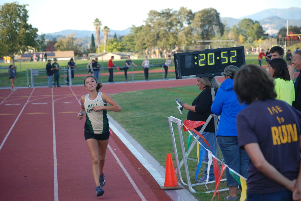 Athlete prepares for pole vault on a track with others watching.