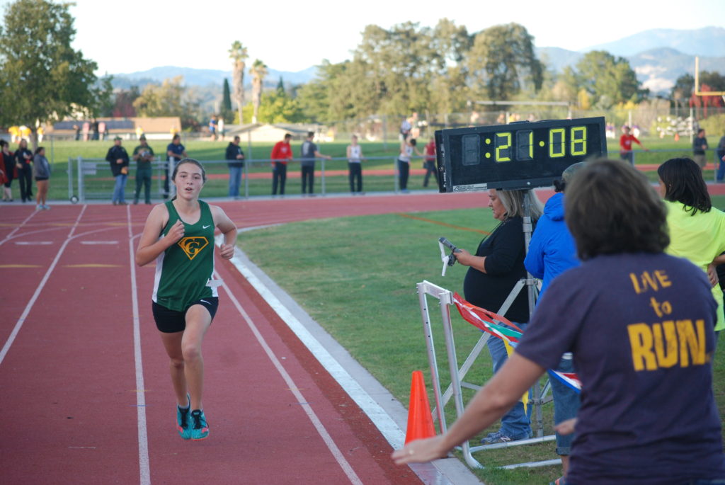 Athlete prepares for pole vault on a track with others watching.
