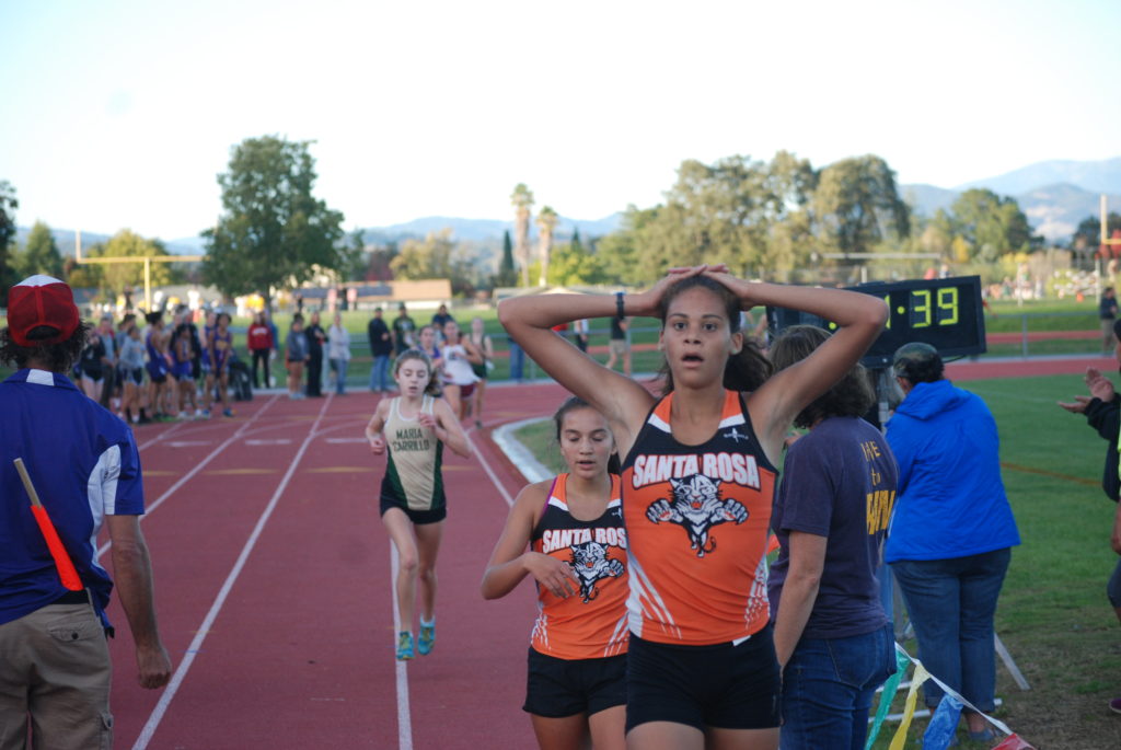 Athlete prepares for pole vault on a track with others watching.