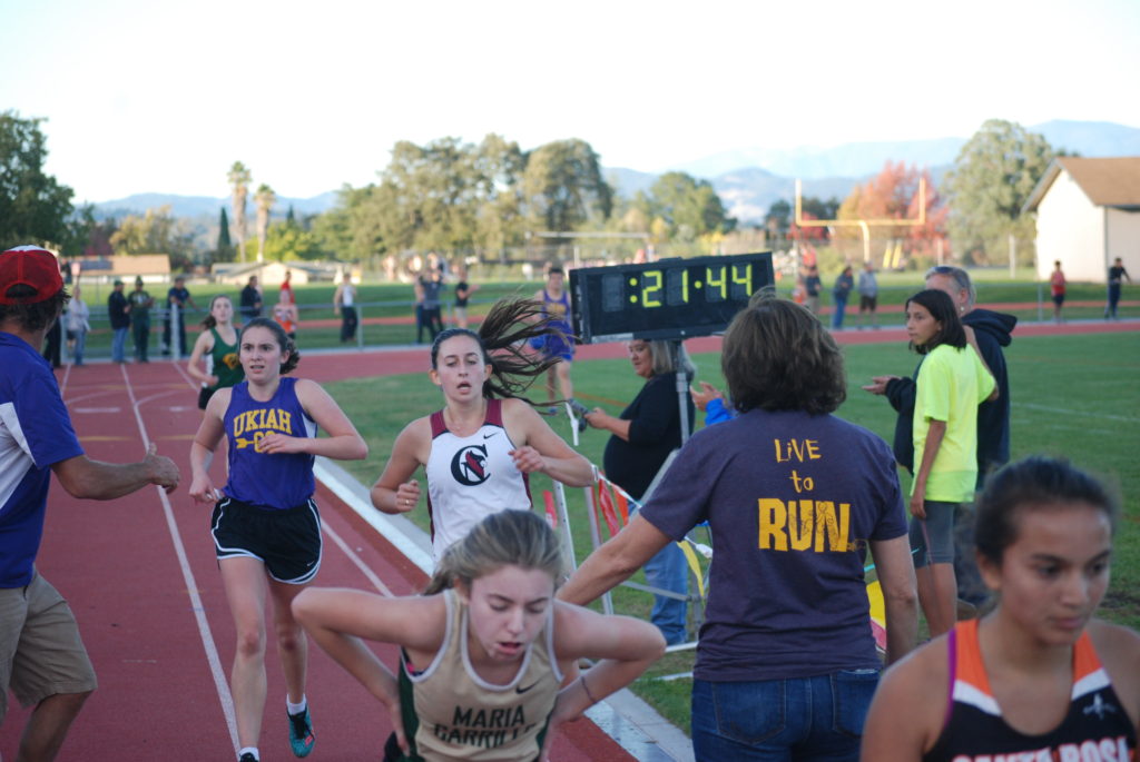 Athlete prepares for pole vault on a track with others watching.