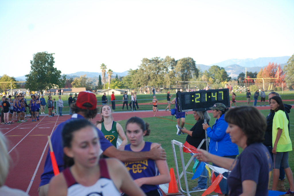 Athlete prepares for pole vault on a track with others watching.