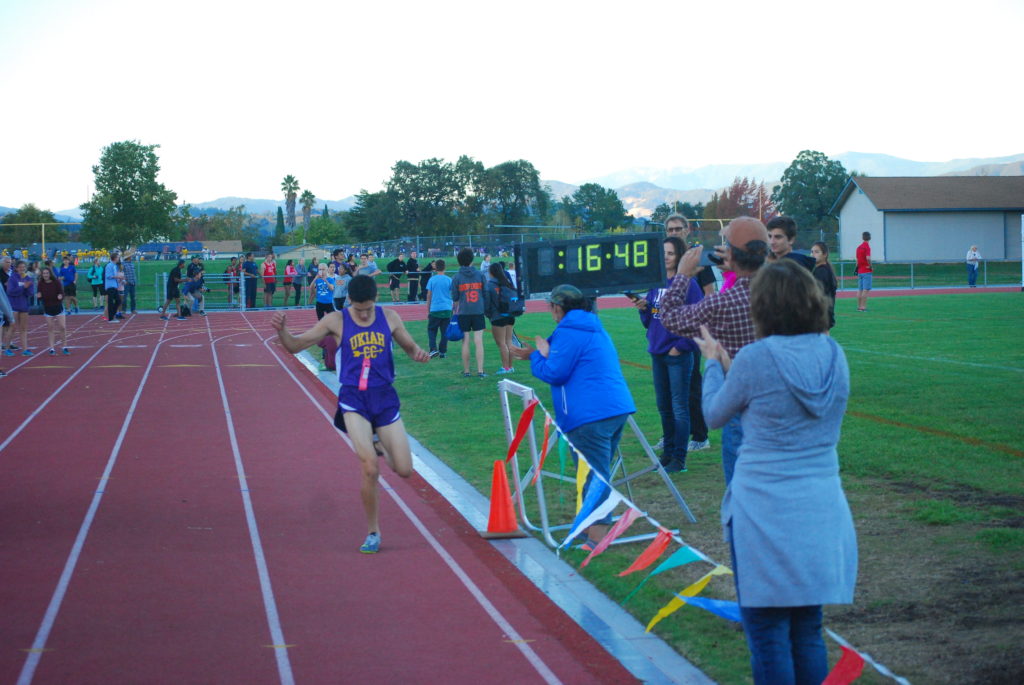 Athlete prepares for pole vault on a track with others watching.