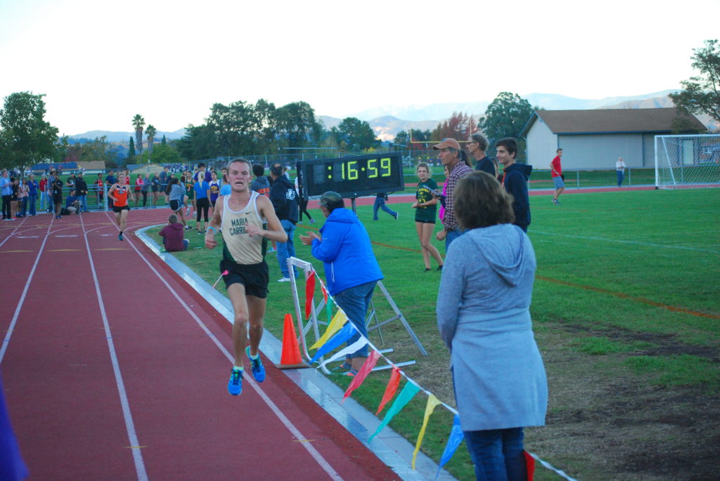 Athlete prepares for pole vault on a track with others watching.