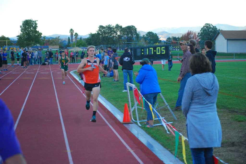 Athlete prepares for pole vault on a track with others watching.
