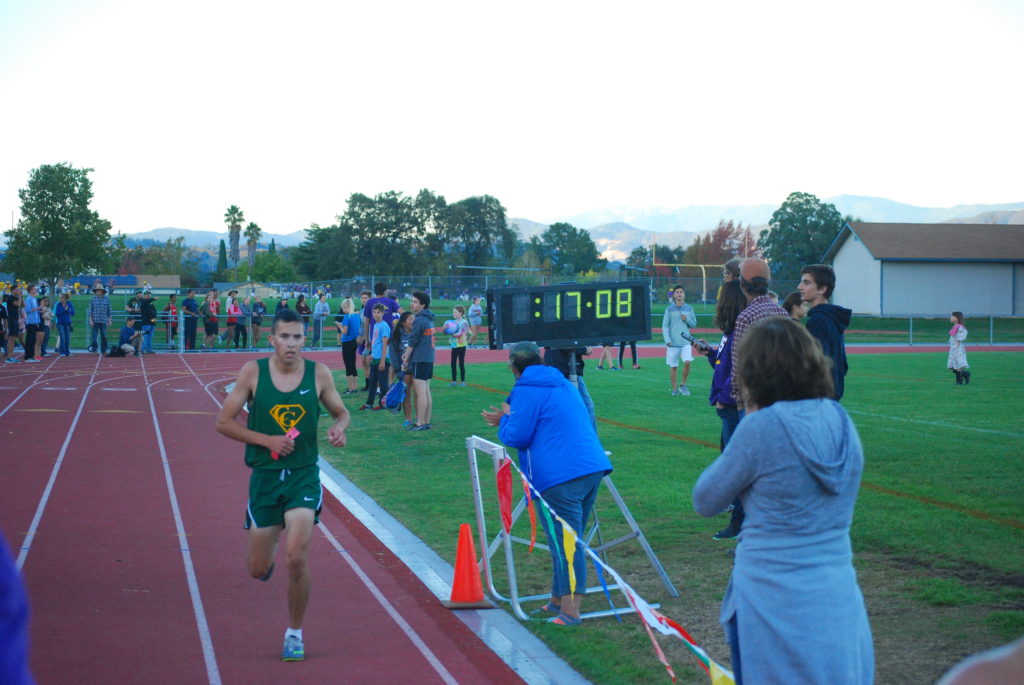 Athlete prepares for pole vault on a track with others watching.
